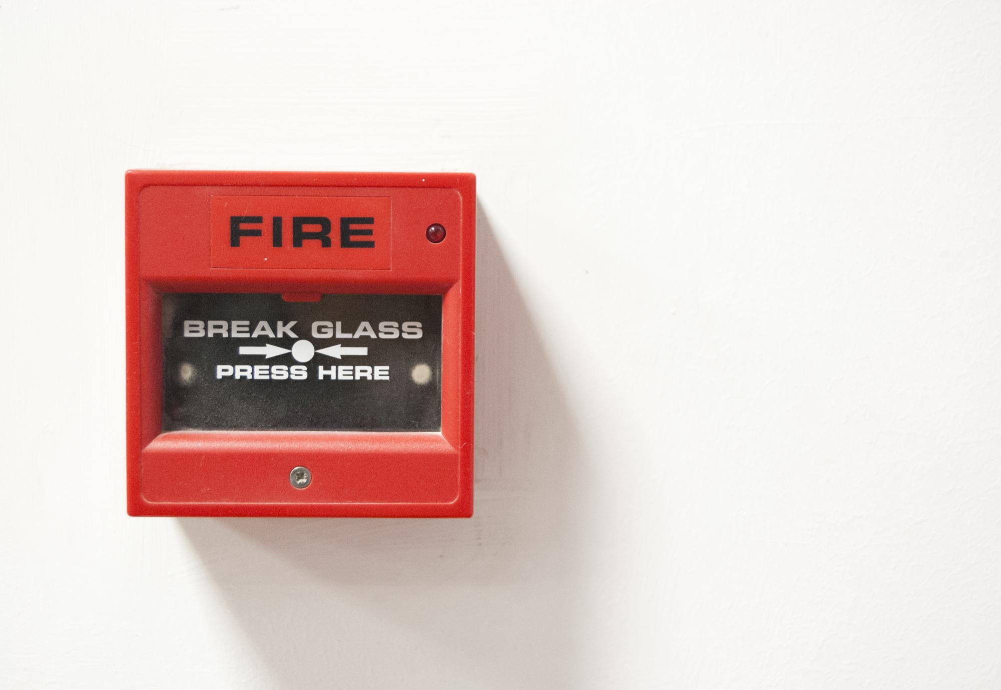 Fire alarm sits on wall ready to be activated. 