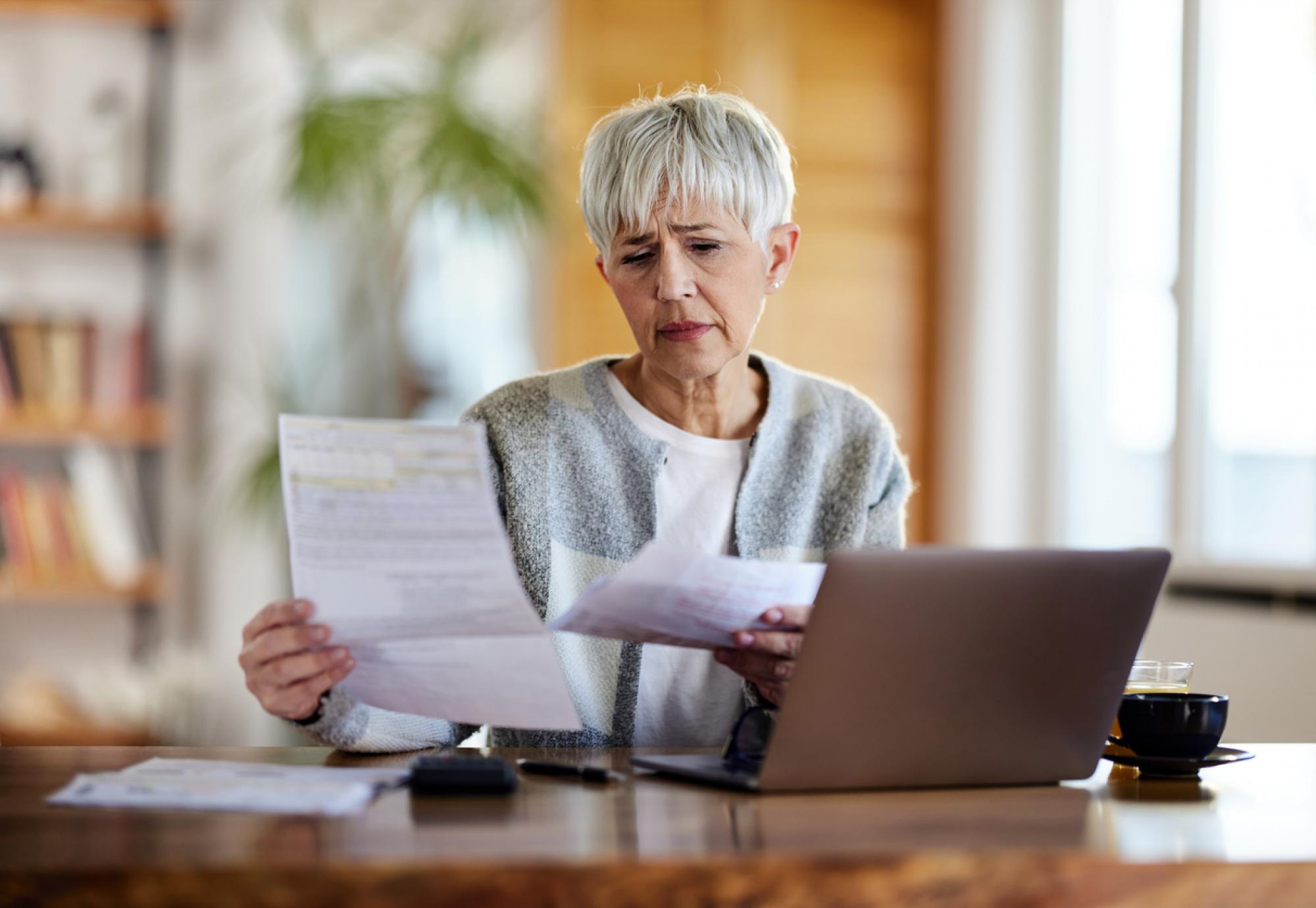 Older woman looking worried when looking at her bills