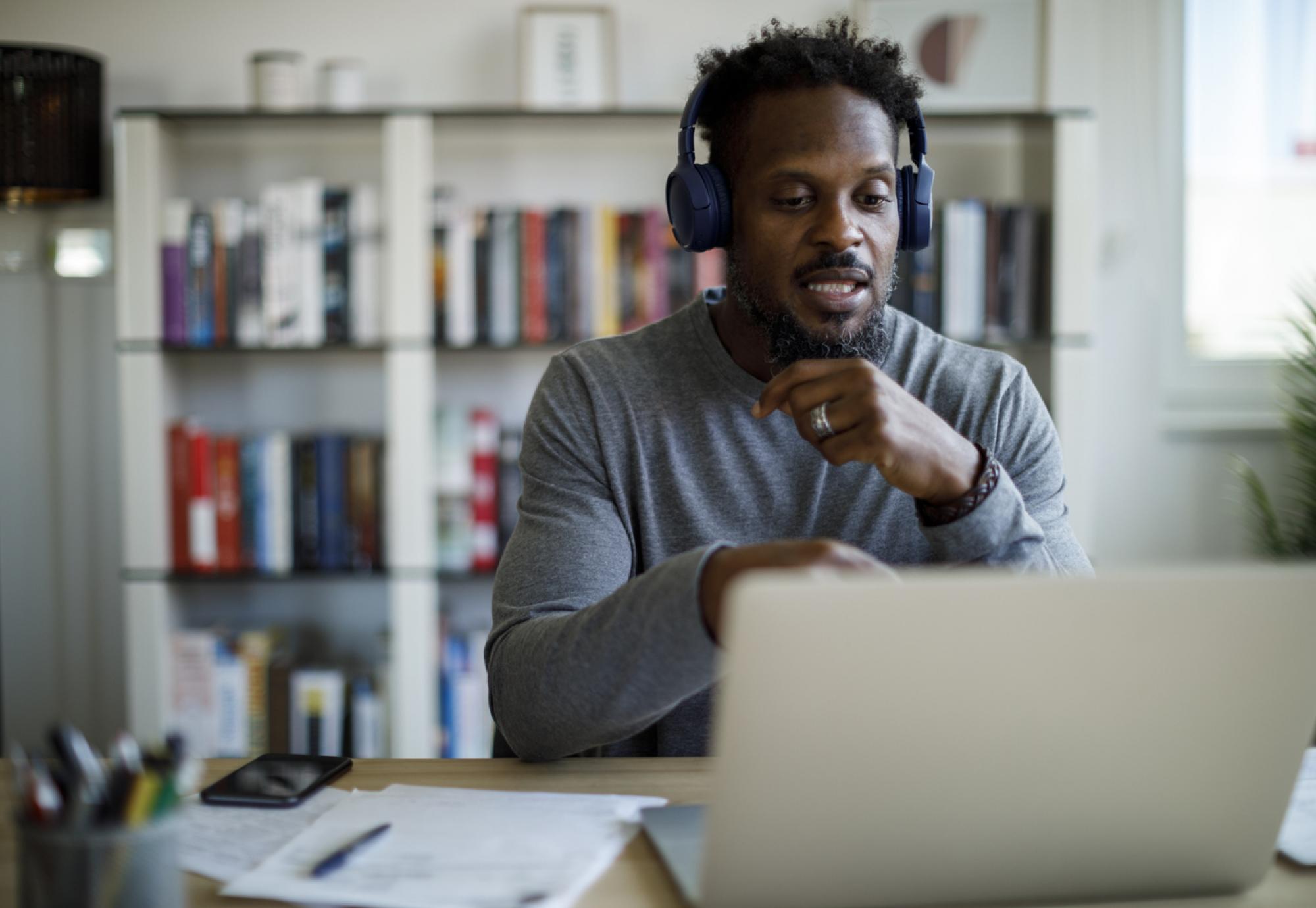 Man with headphones attends an online course at home