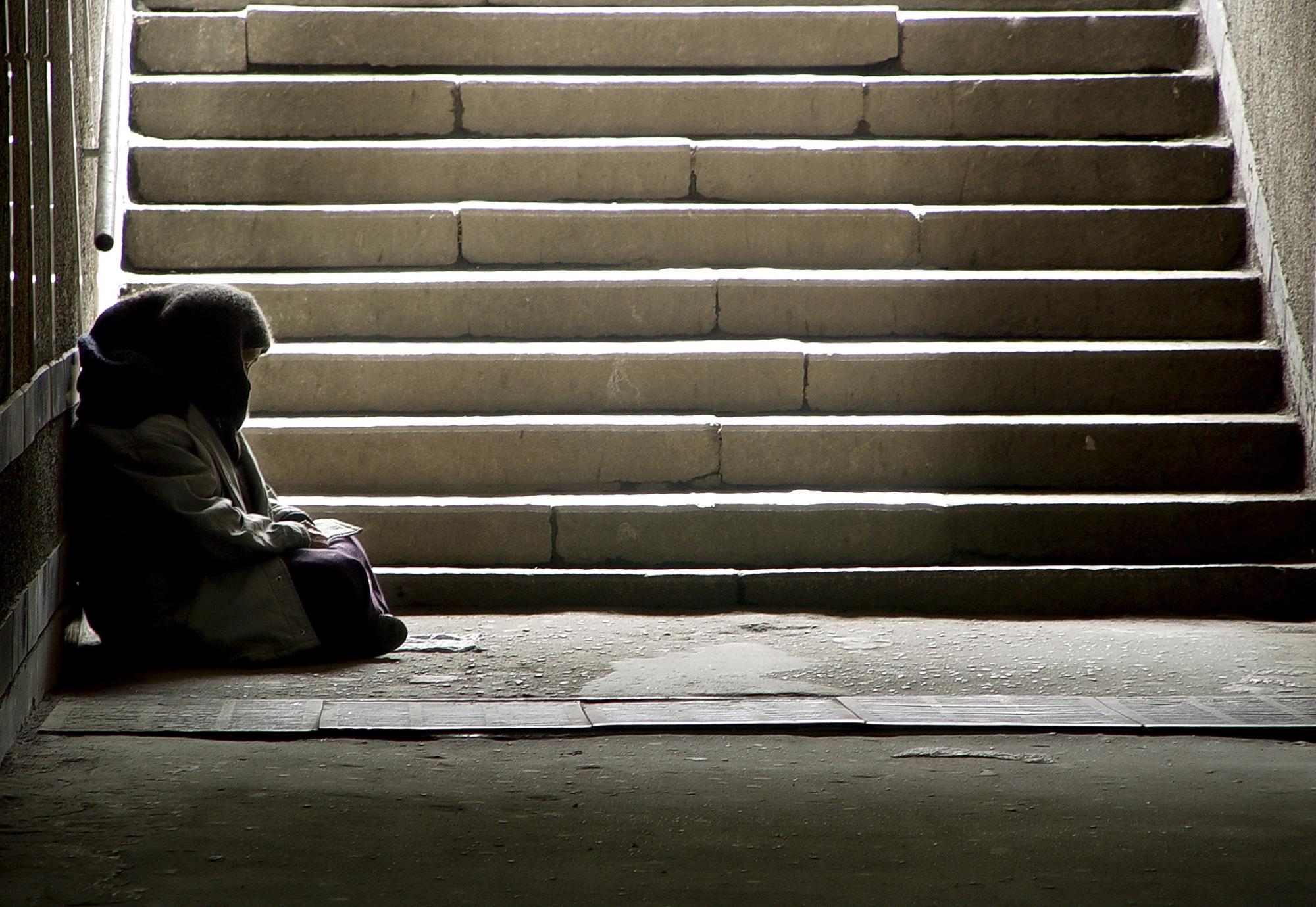 Homeless woman sitting on the floor by some steps