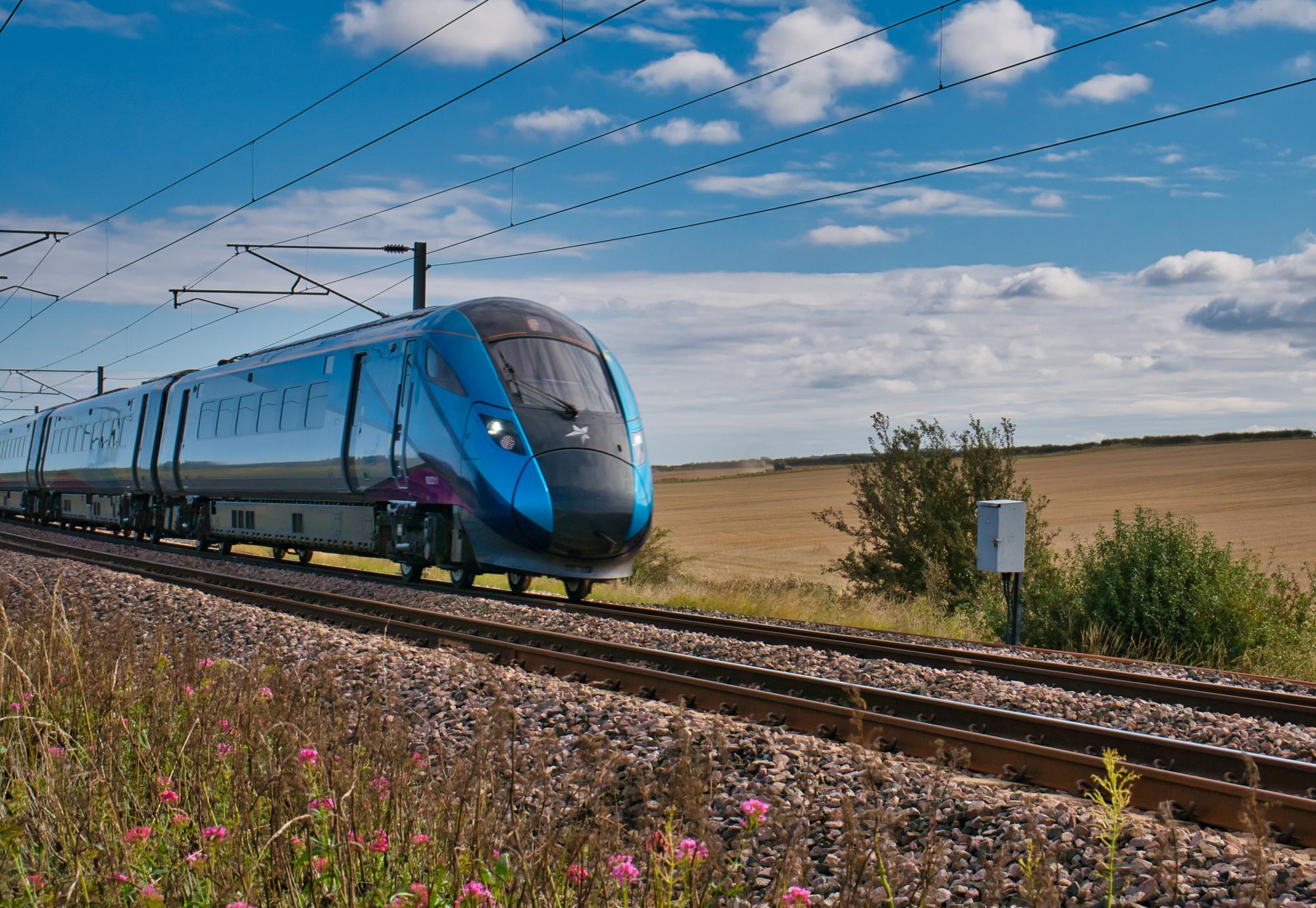 Transpennine Express train travelling at speed in Northumberland, UK - taken on a sunny day with white clouds.