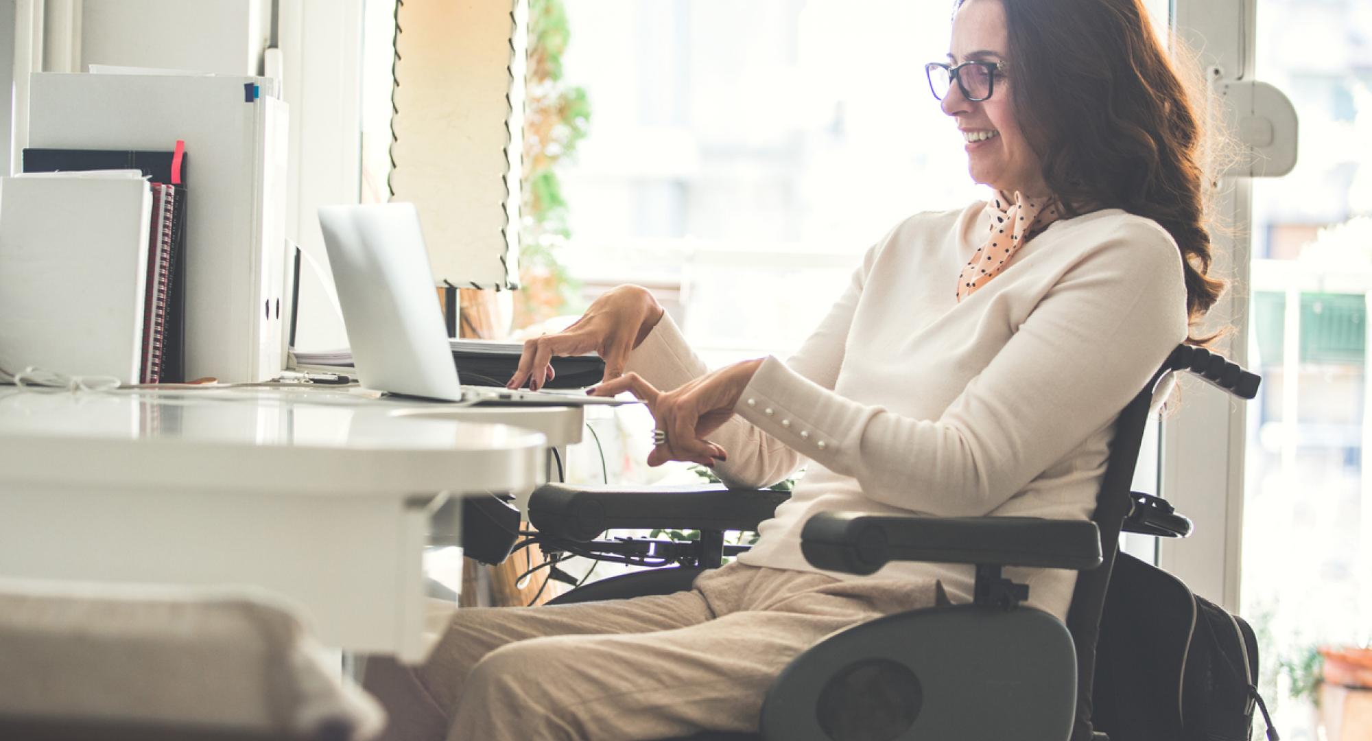 Side view of a happy woman with physical disability working on a laptop