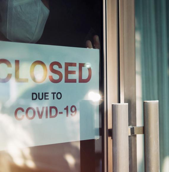 Person puts sign up that says "Closed due to Covid" in their shop window.
