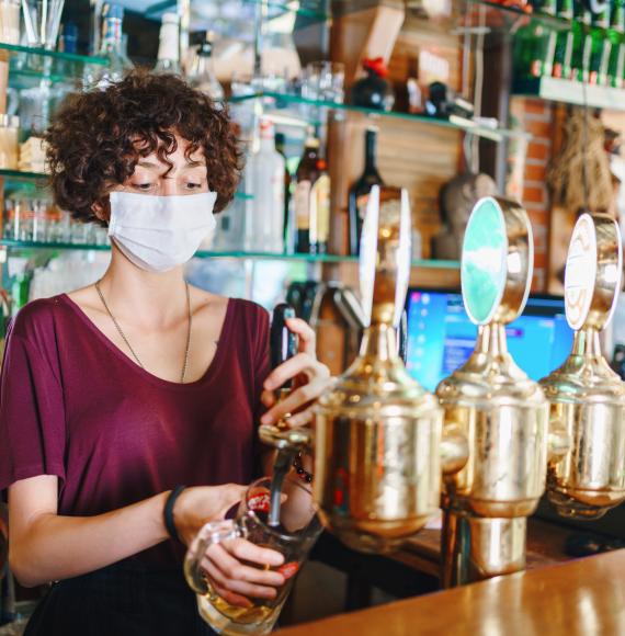 Woman with face mask pulls a pint