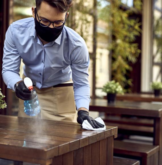 Waiter cleans table with antibacterial spray and wipe.