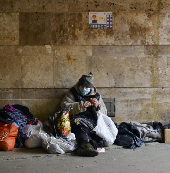 Homeless person sits against the wall in winter.