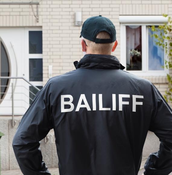 Bailiff stands in front of house ready to knock. 