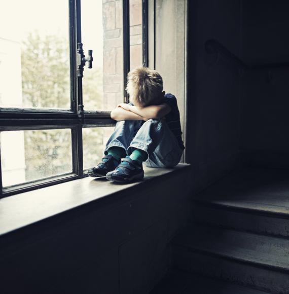 Lonely child sits in window. 