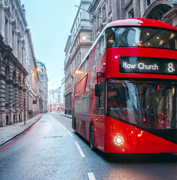 Bus drives down empty London street. 
