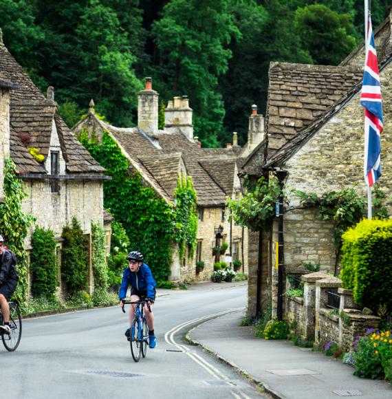 Cyclists riding bikes through a village in Cotswolds