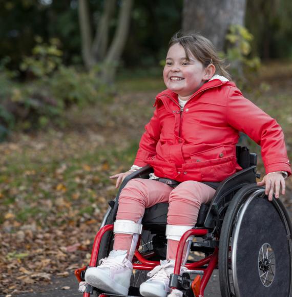 Picture of a young girl in a wheelchair in a public park