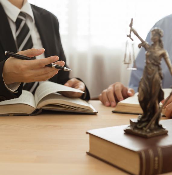 Two lawyers working, justice statue sits in the foreground on the table