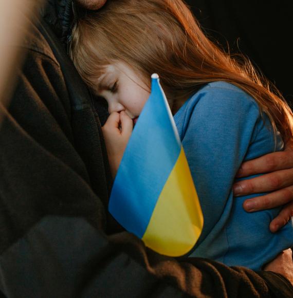 A Ukrainian refugee child with a Ukraine flag
