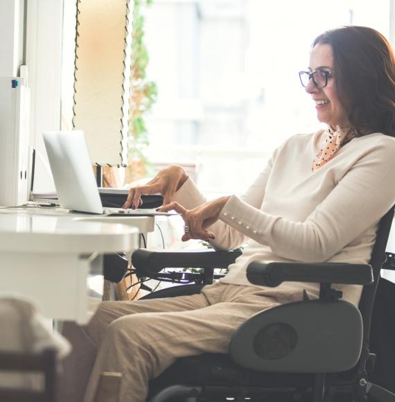 Side view of a happy woman with physical disability working on a laptop