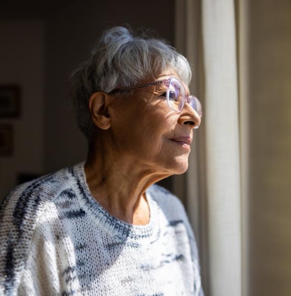 Senior woman looking out the windows of her home