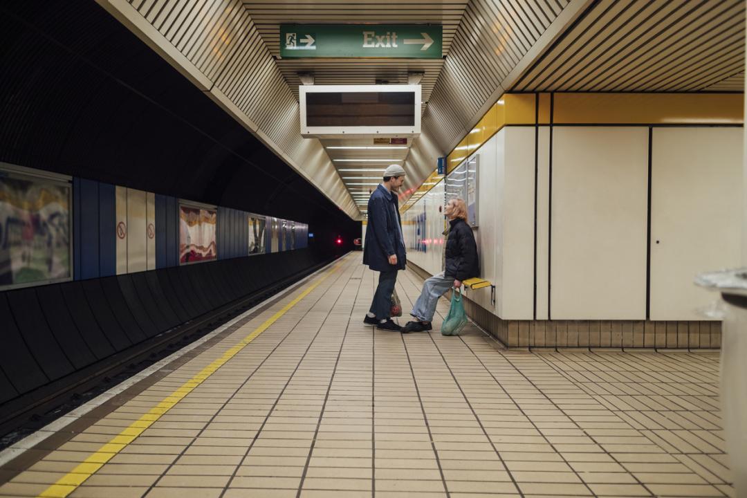 two young people stood on the platform of a metro station