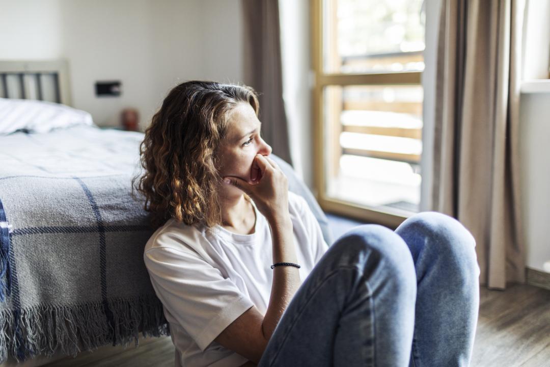 A woman sat on the floor looking sad