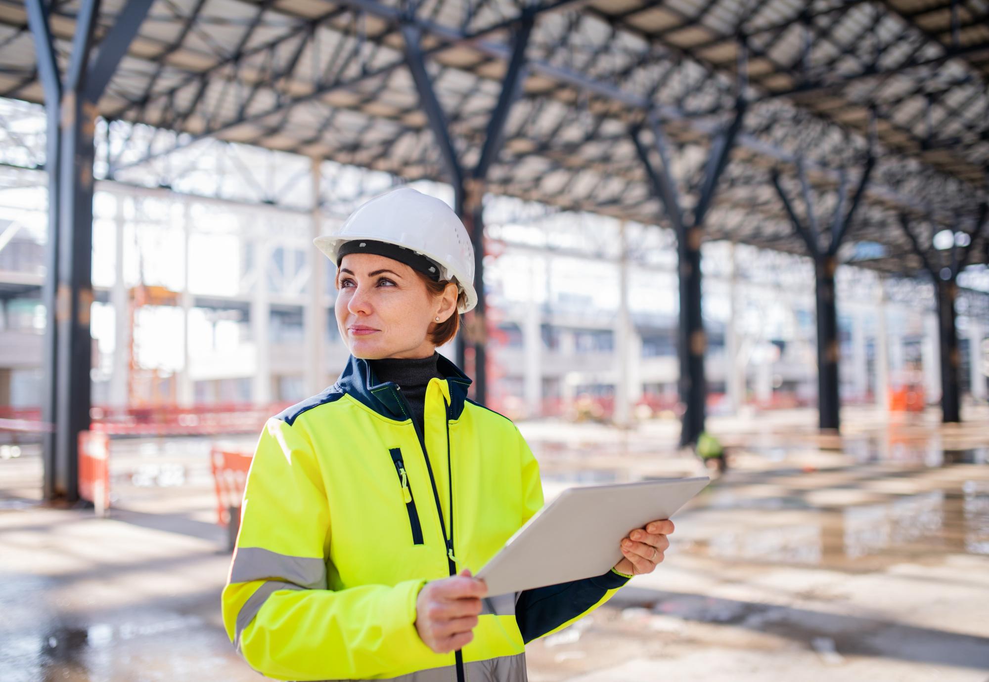 A woman engineer with tablet standing on construction site, working.