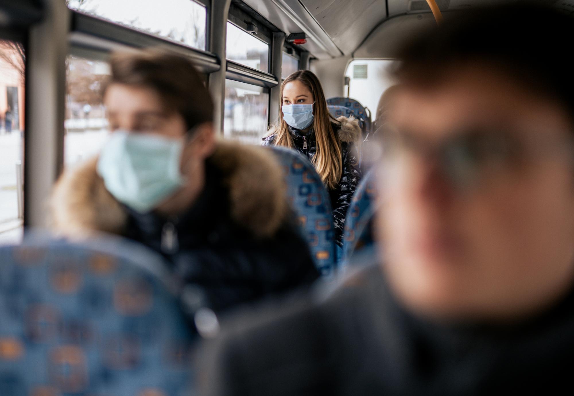 Woman in mask on a bus blurred focus foreground