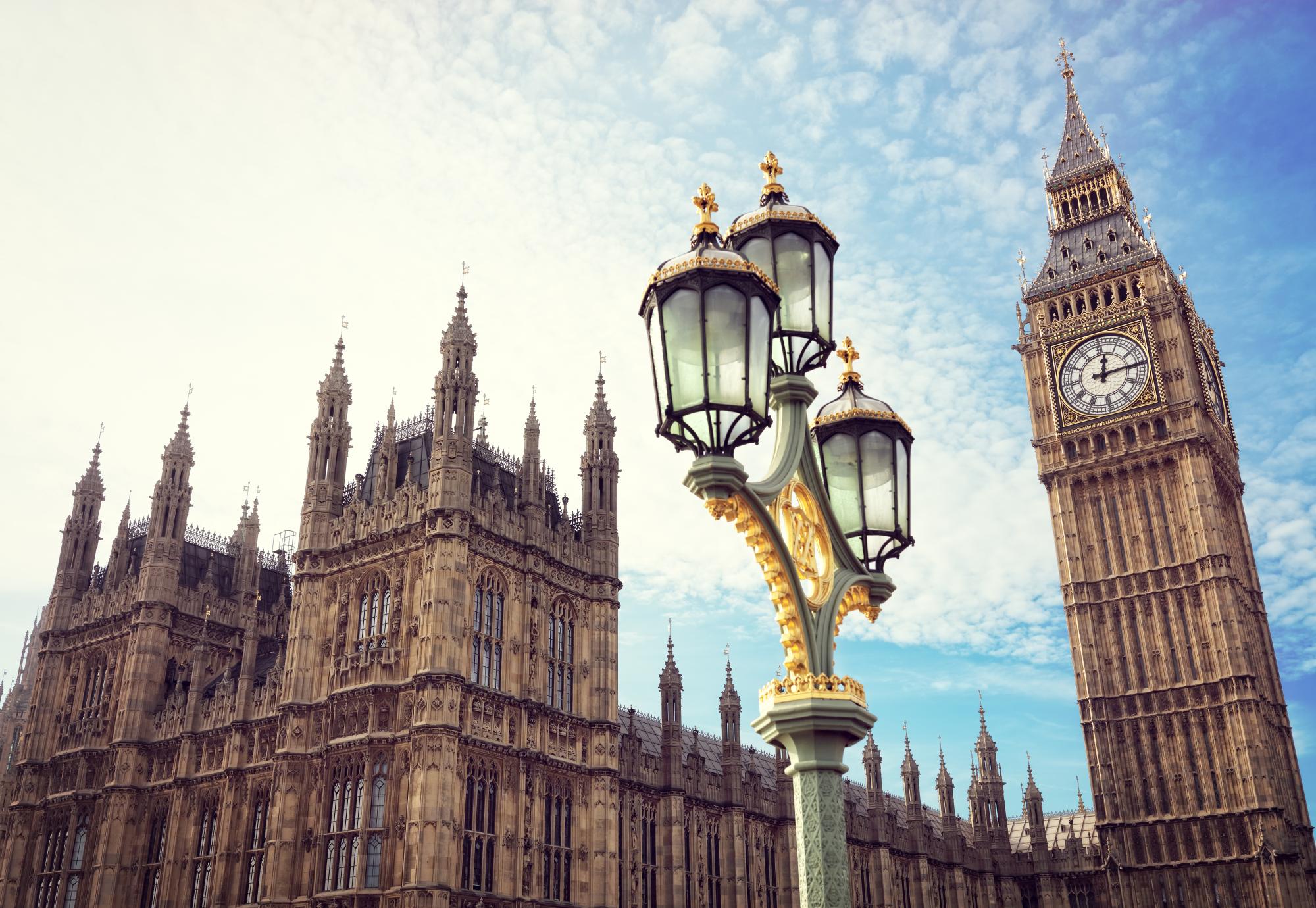Big Ben in London with the houses of parliament and ornate street lamp.