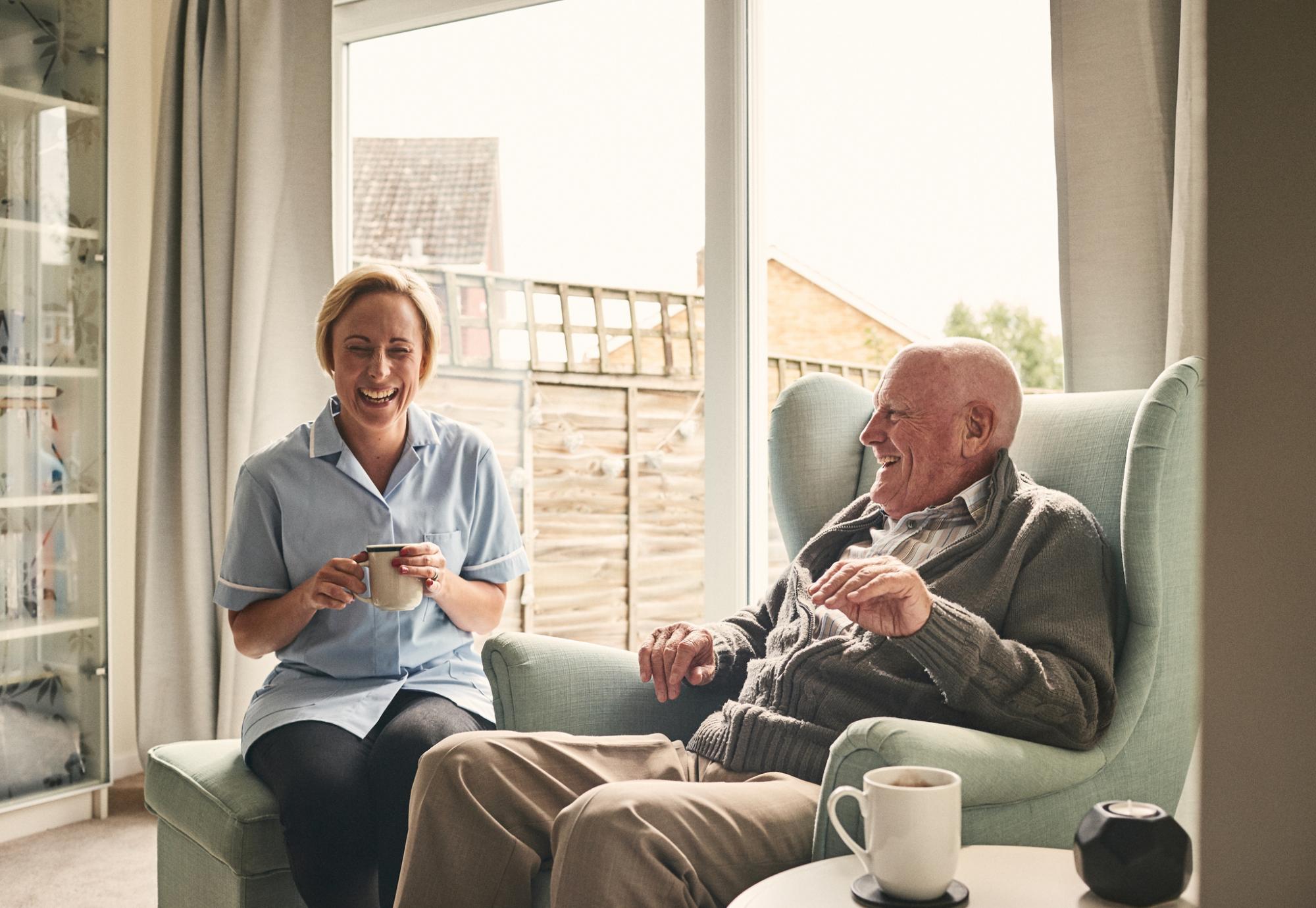 carer nurse laughing with older gentleman