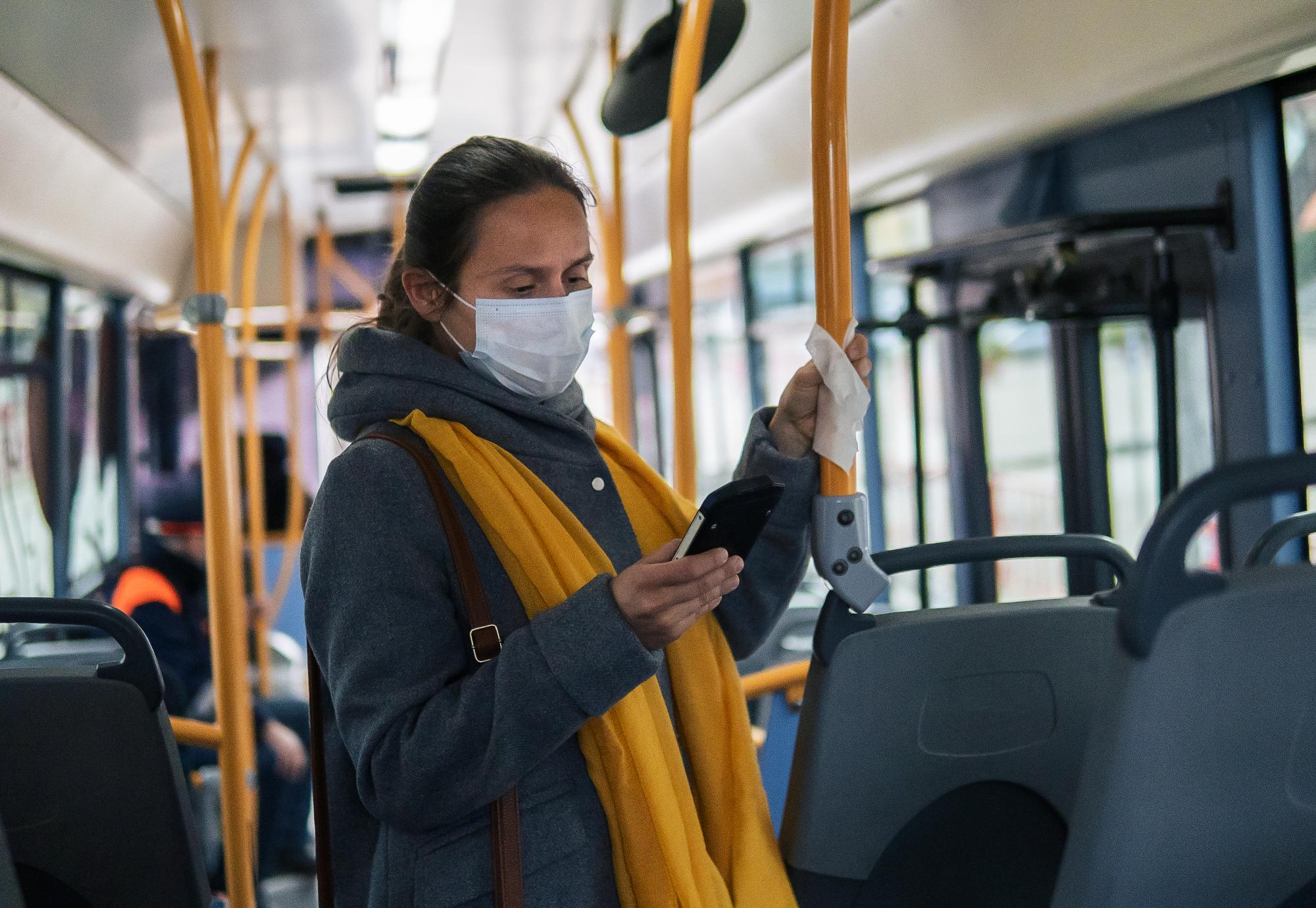 Woman stands  on bus in mask
