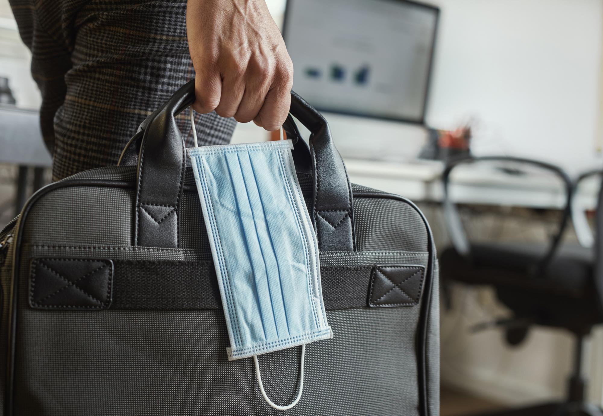 Man carries mask and briefcase 