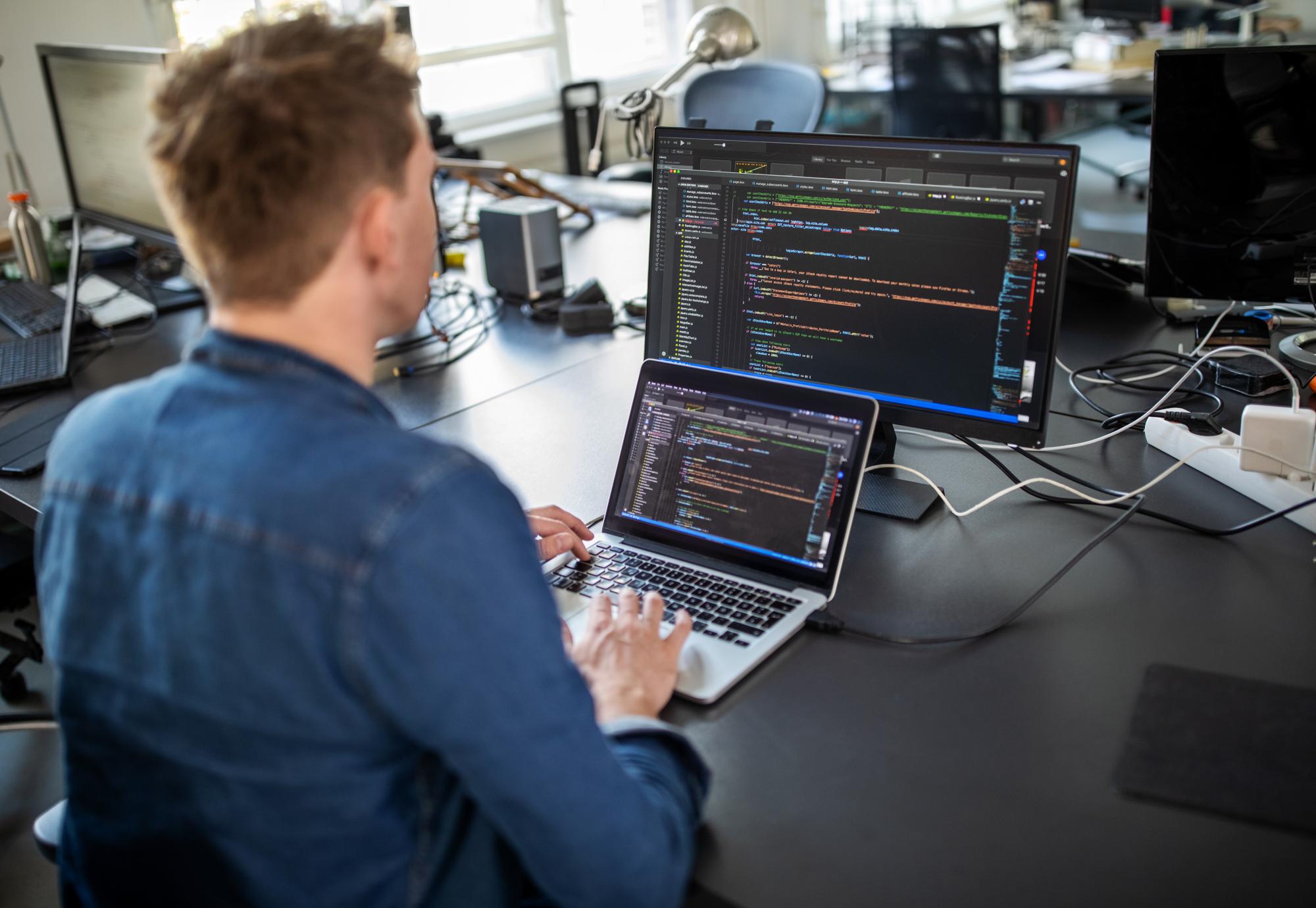 Man sits at computer coding.