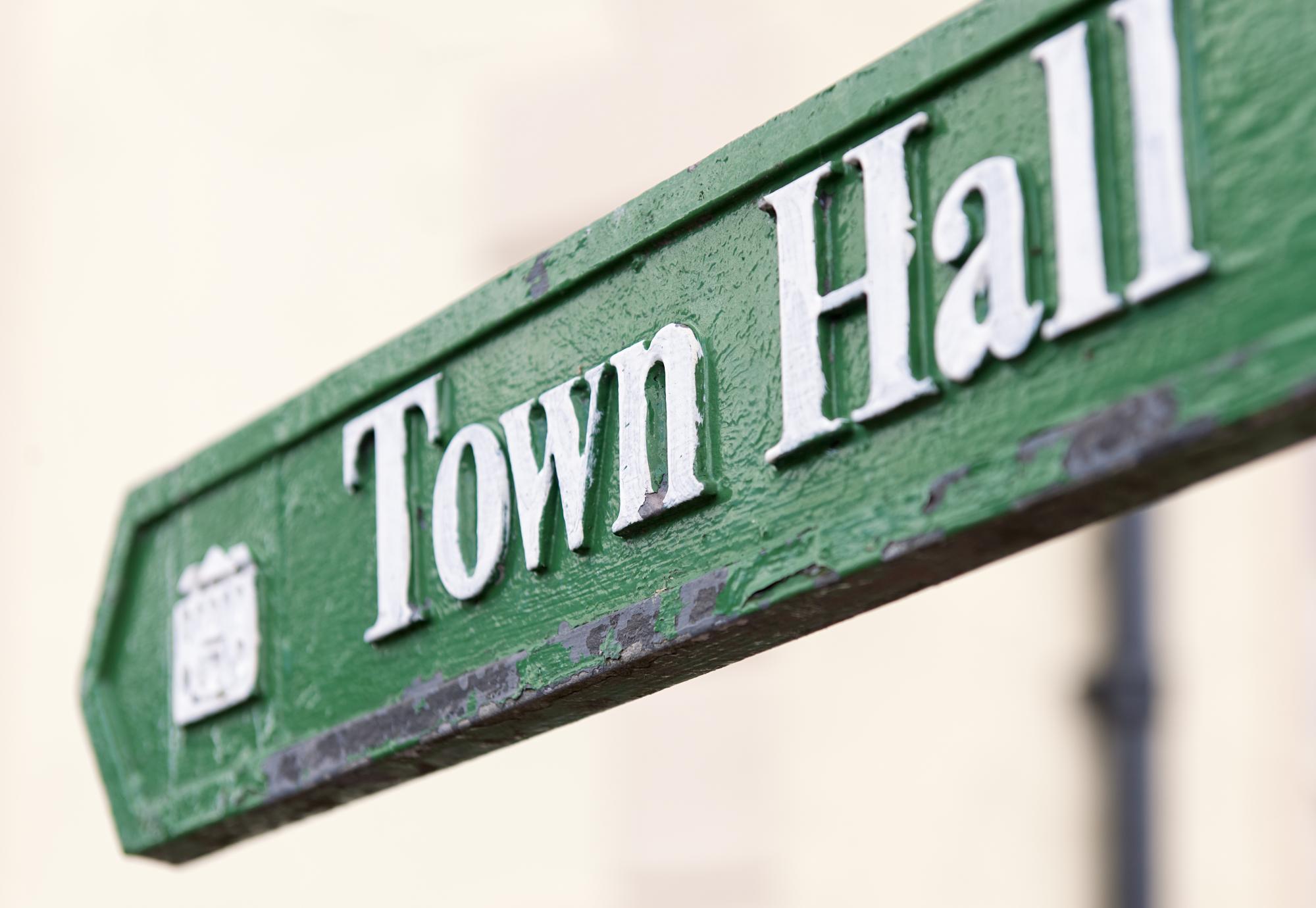 Close-up of a traditional, worn sign showing the direction to the town hall.