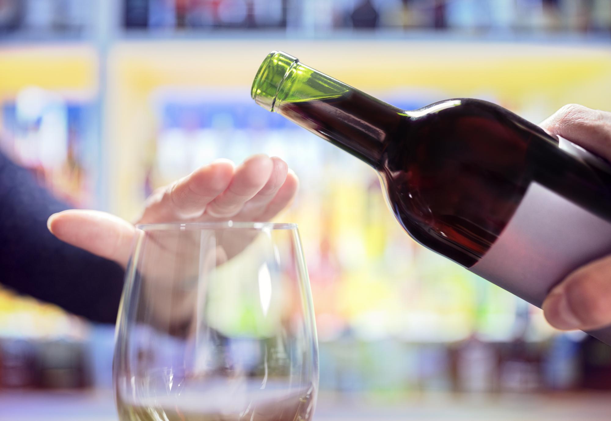 Person with hand over glass, refusing wine.