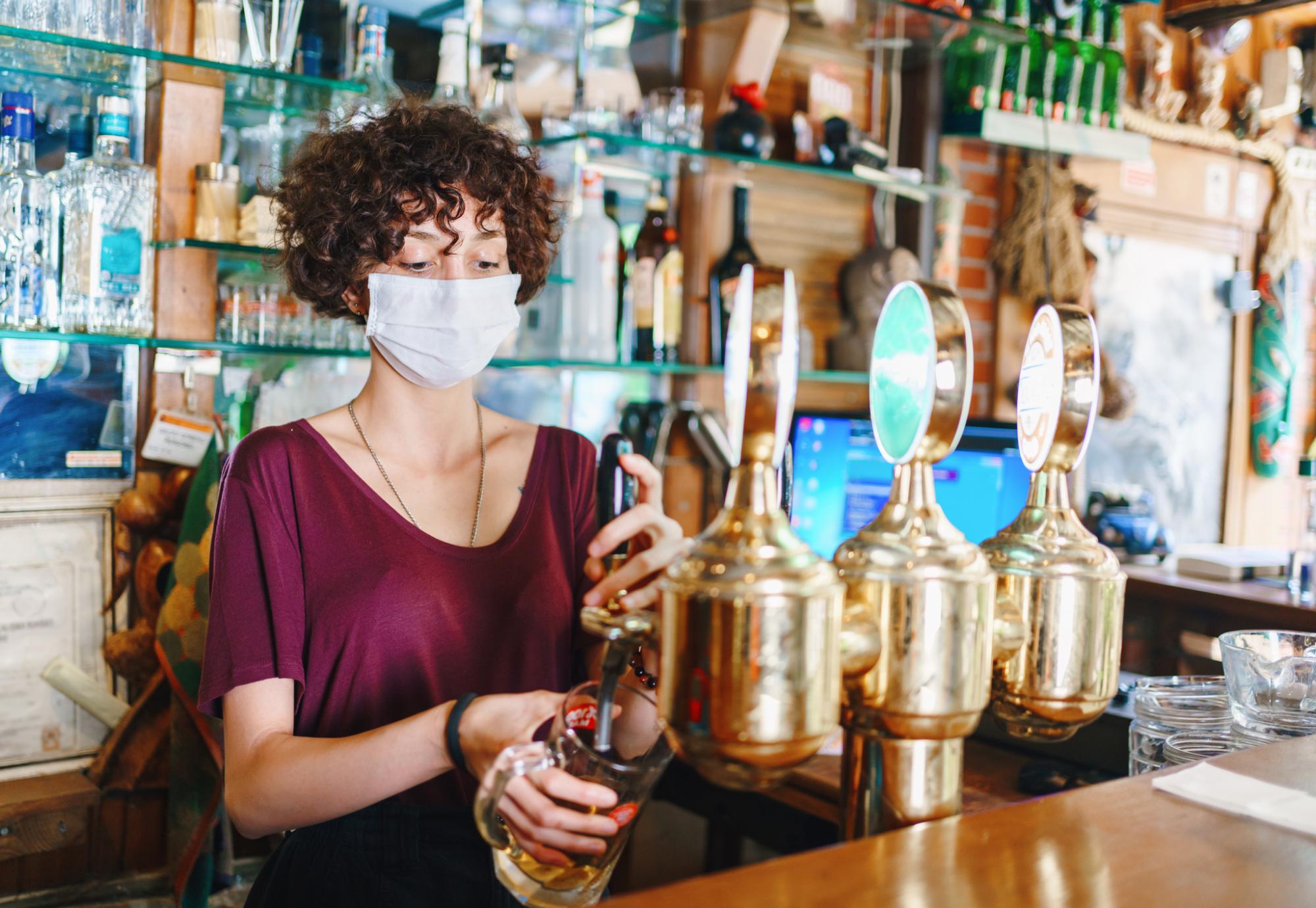 Woman with face mask pulls a pint