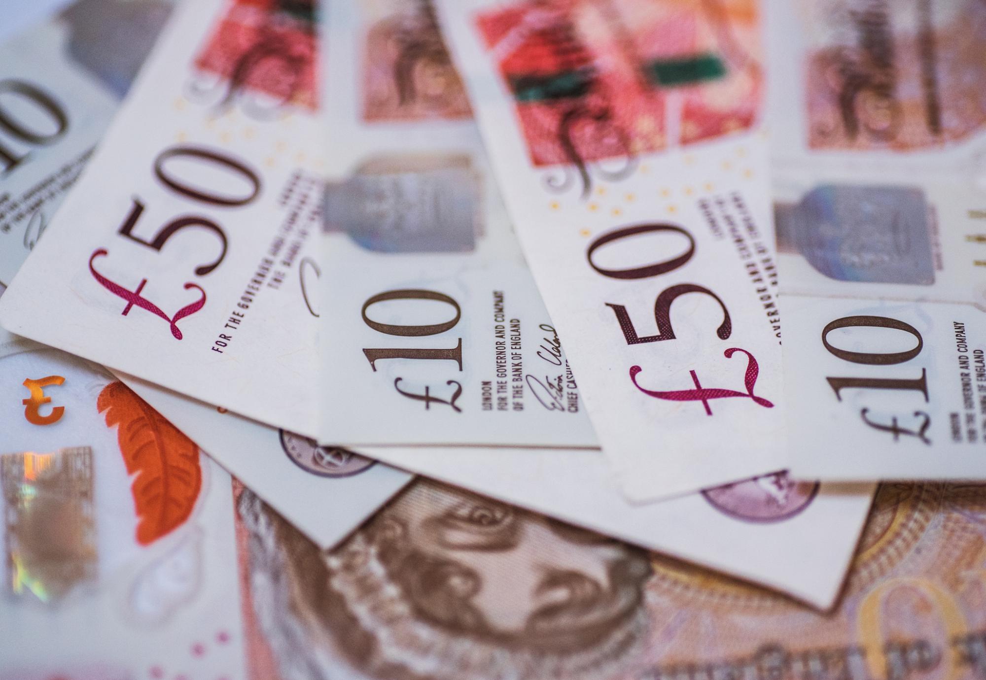 Picture of 10 and 50 pound notes scattered across a table.