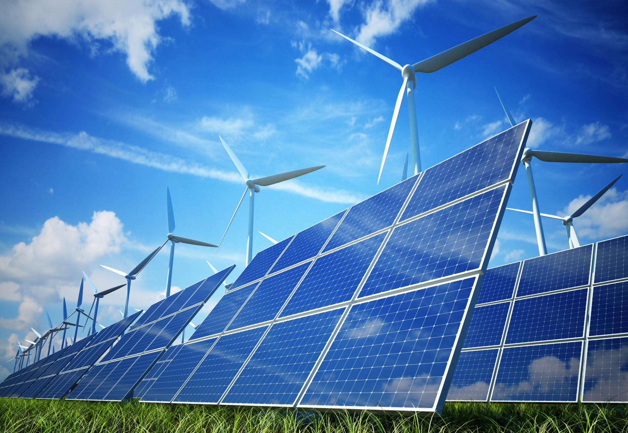 Solar plant in the sun with wind turbines in the backgroud.