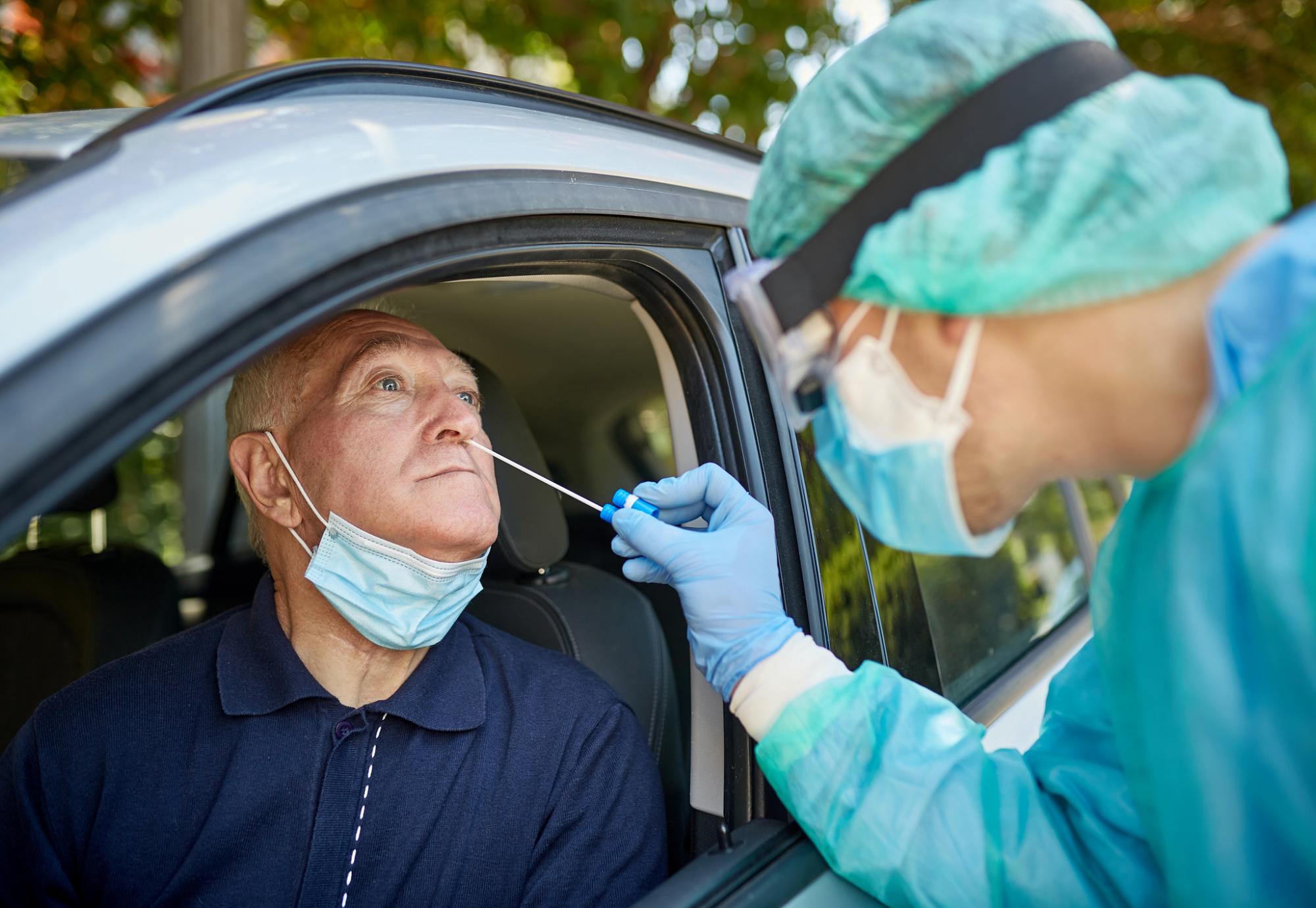 Man receives Covid-19 test from woman wearing full PPE