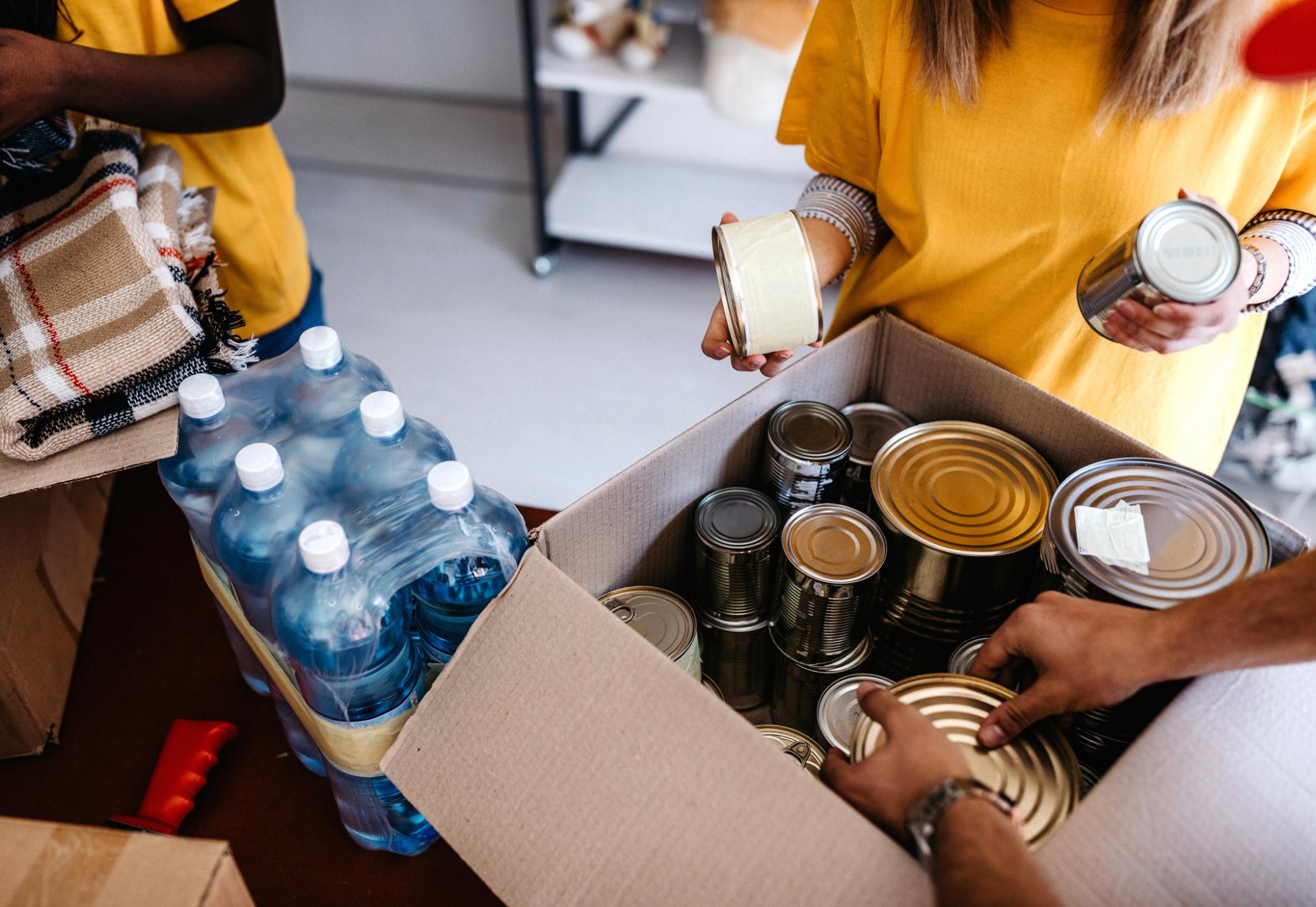 Food bank volunteers pack a box of food.