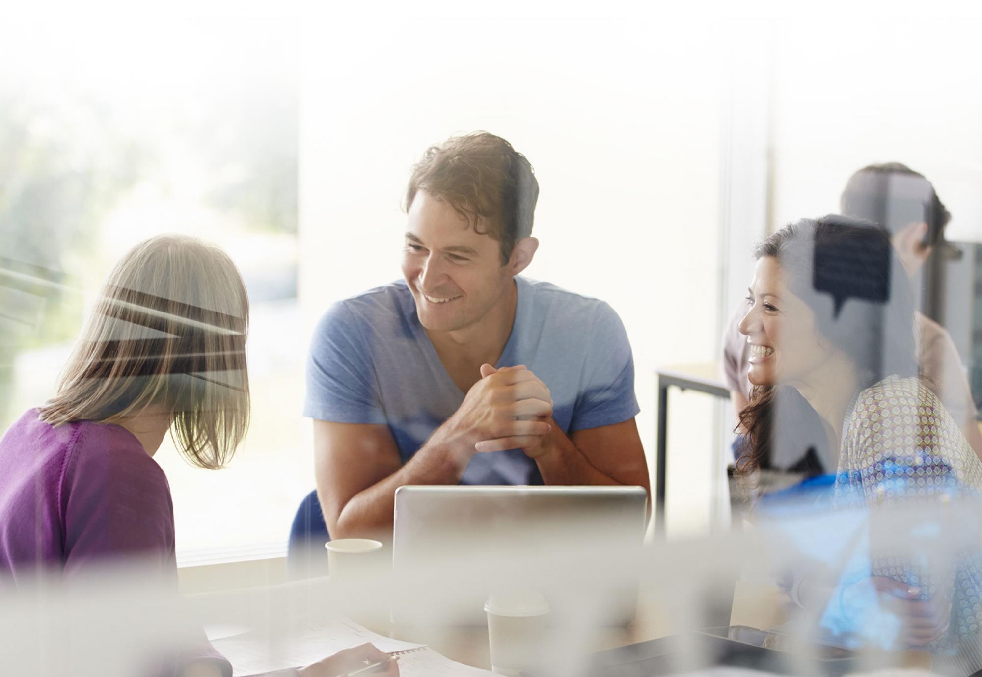 Colleagues sit and chat over office work.