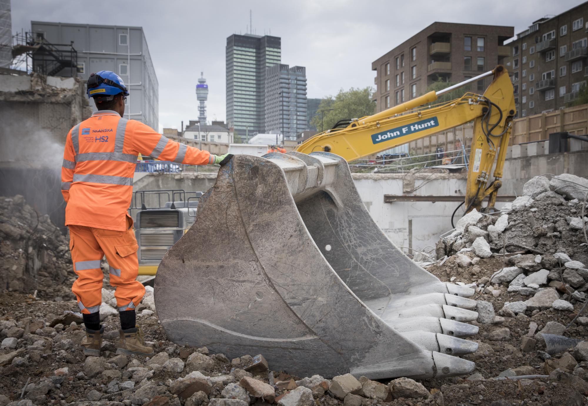 Man stands next to digger working on HS2 at London Euston