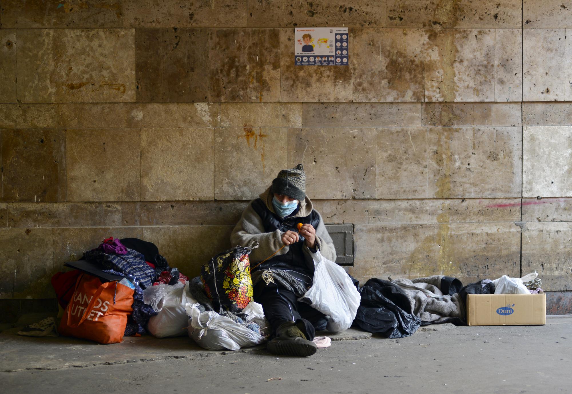 Homeless person sits against the wall in winter.