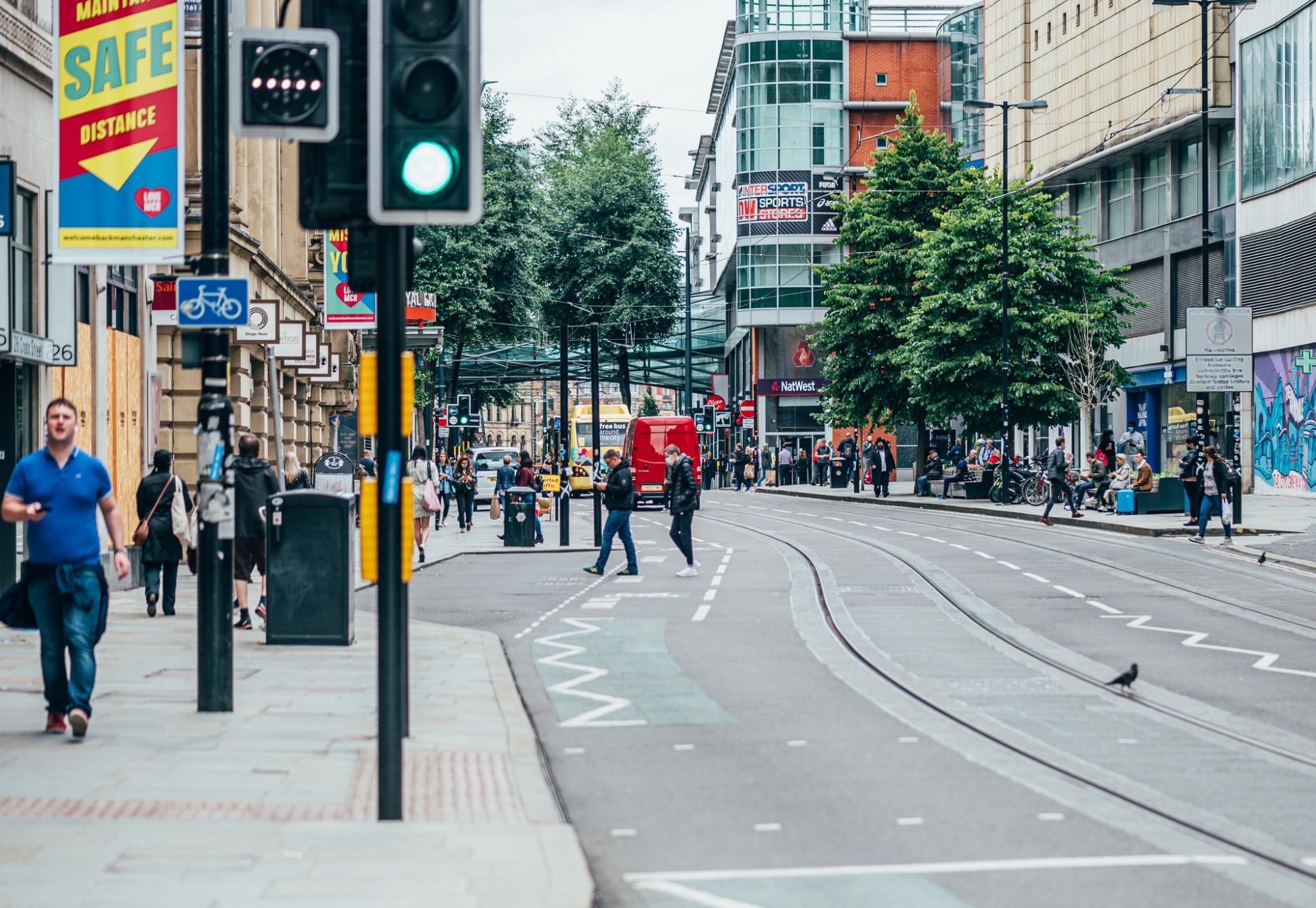 Busy Manchester street with pedestrians on the pavement.