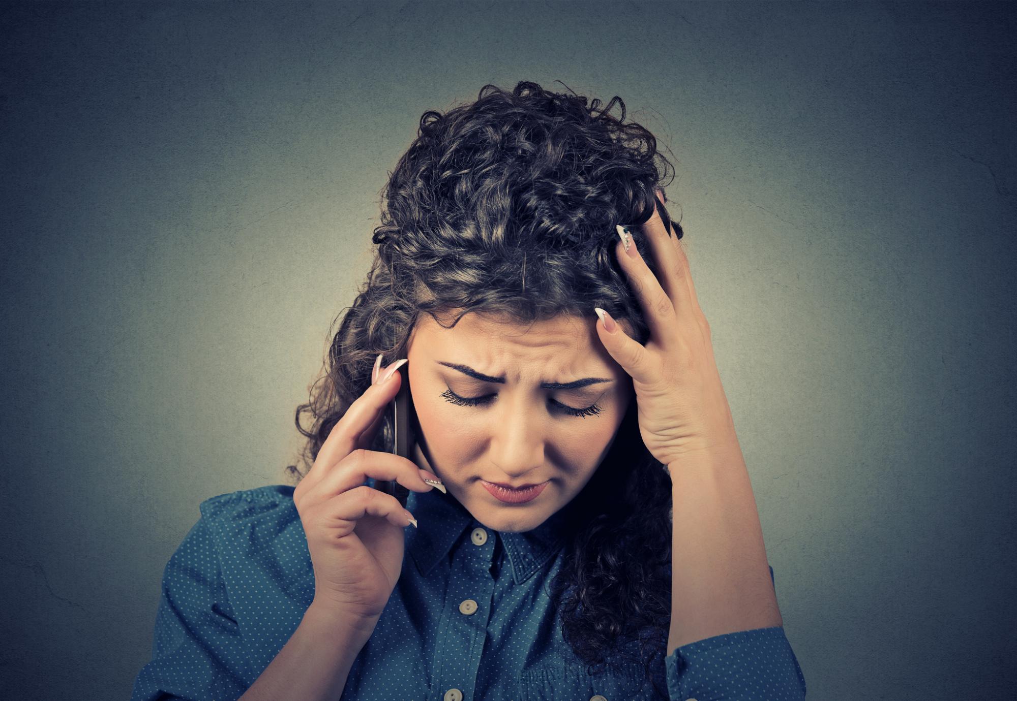 Woman looks distressed on the phone to helpline.