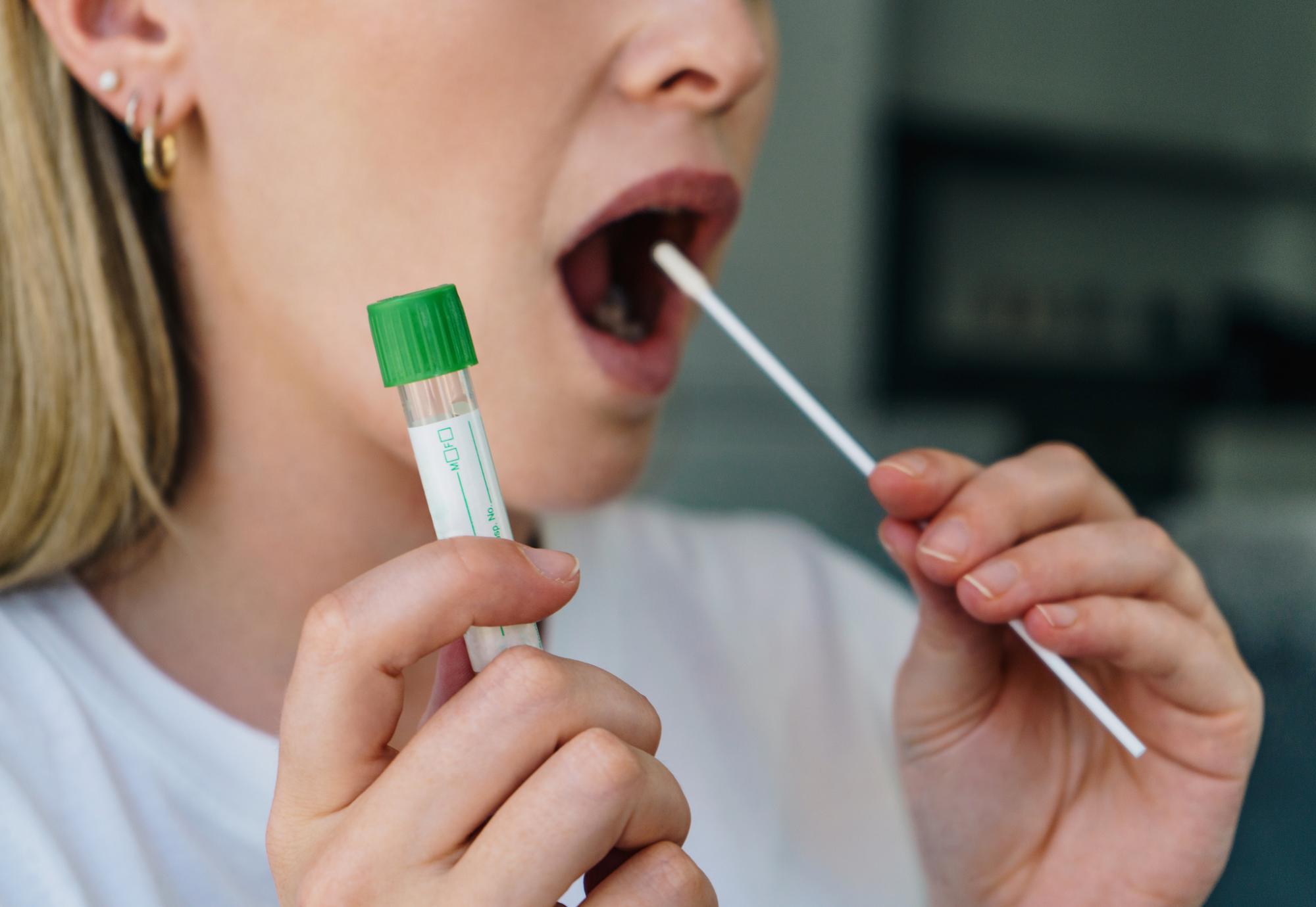 Woman inserts Covid-19 test into her mouth. 