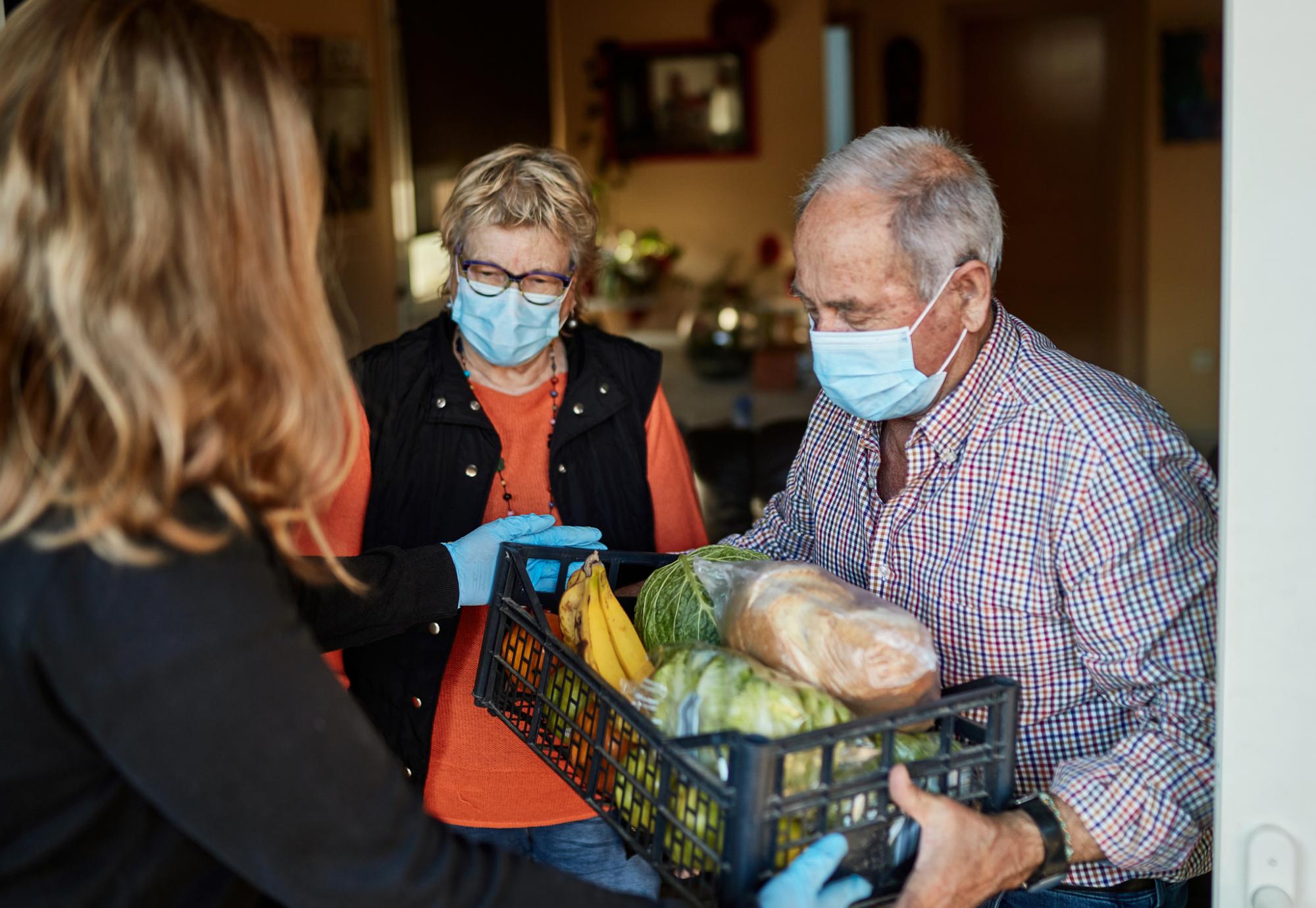 Elderly couple get their food delivery by social care worker.