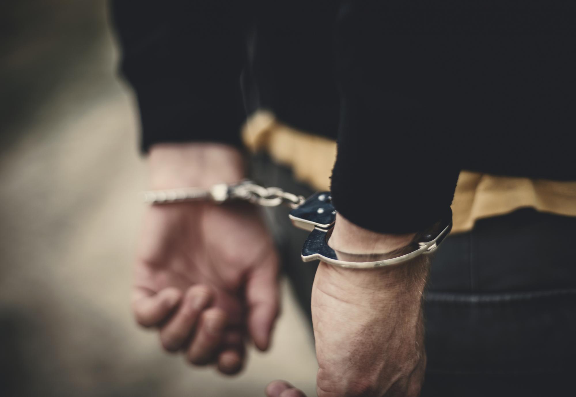 Man with arms behind his back in handcuffs.