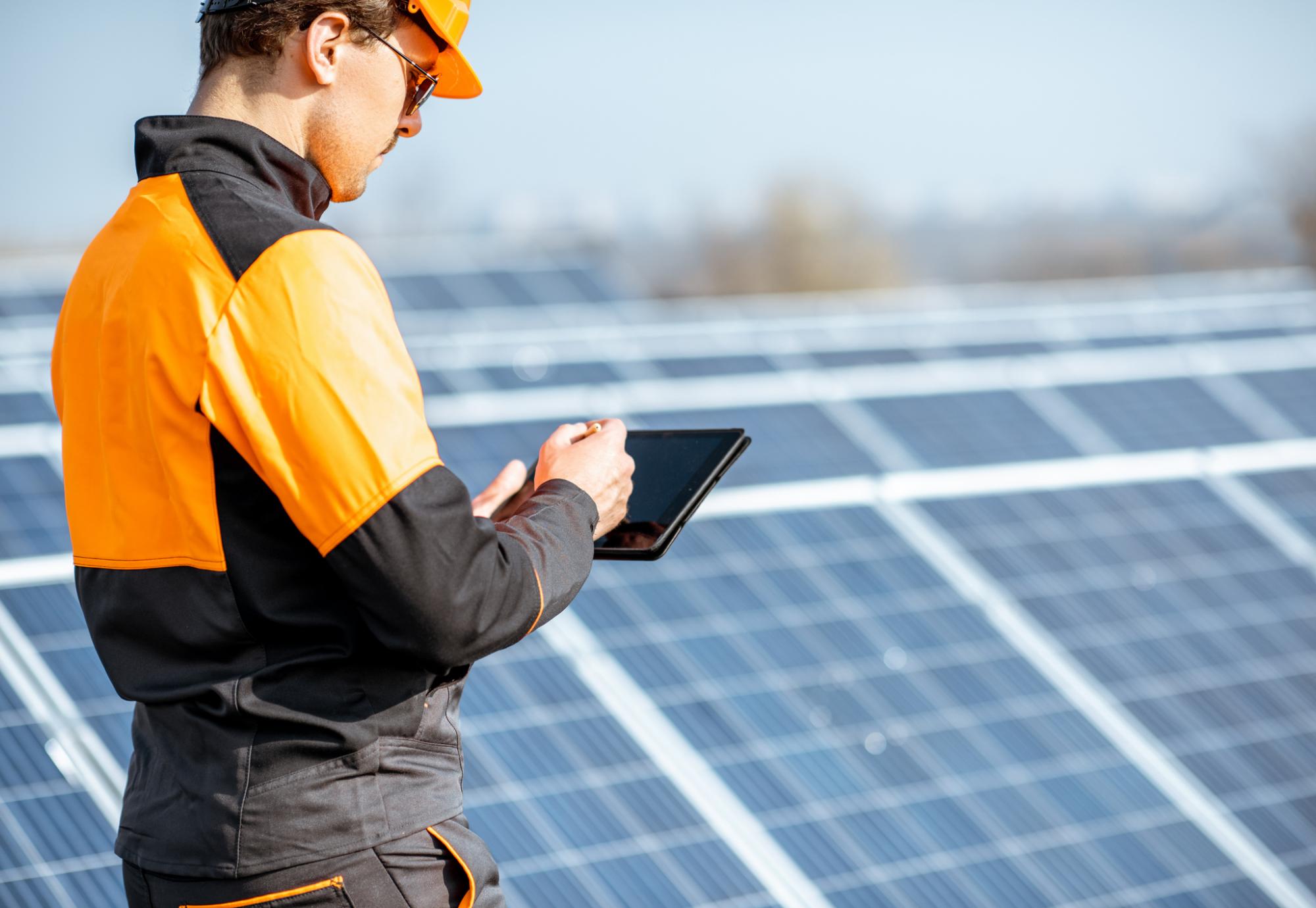 Worker makes note son solar panels that have been installed