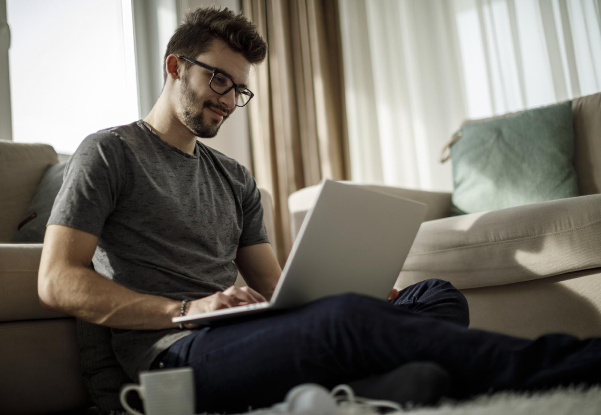 Man sits on his laptop at home doing online course.