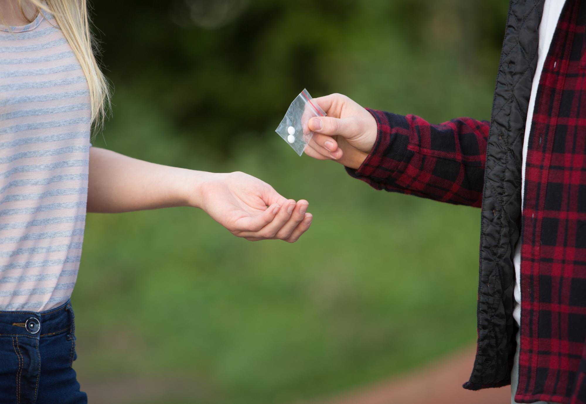 Man hands pills to woman.