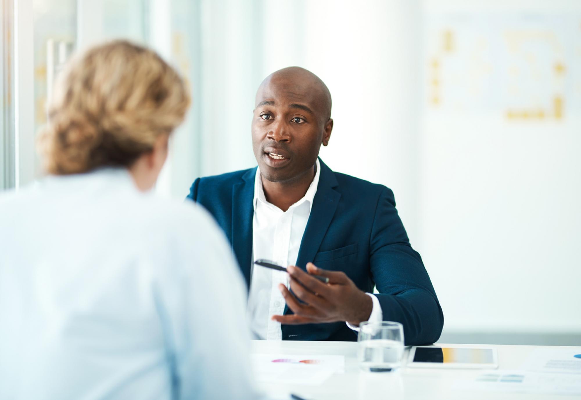 Man gives legal advice to woman in his office. 