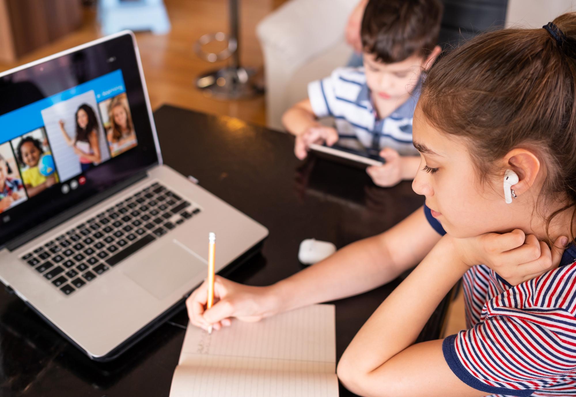 Children sit at laptop e-learning. 