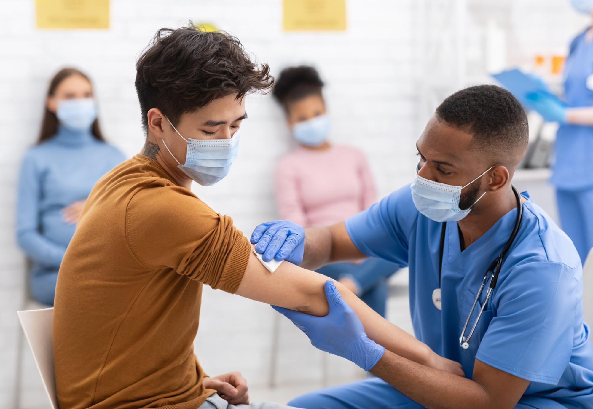 BAME man receives vaccine from nurse.