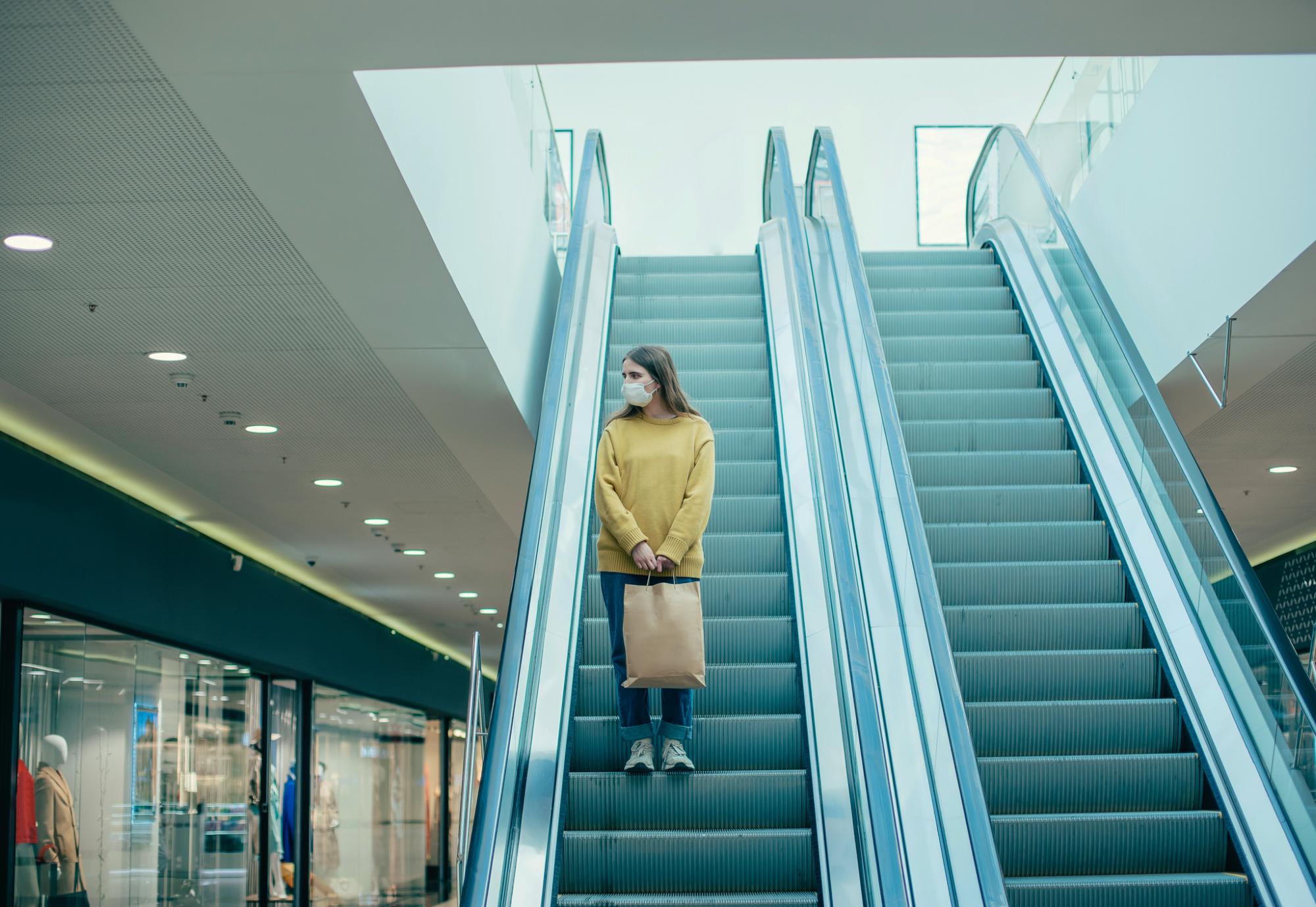 Woman standing on shopping centre escalators